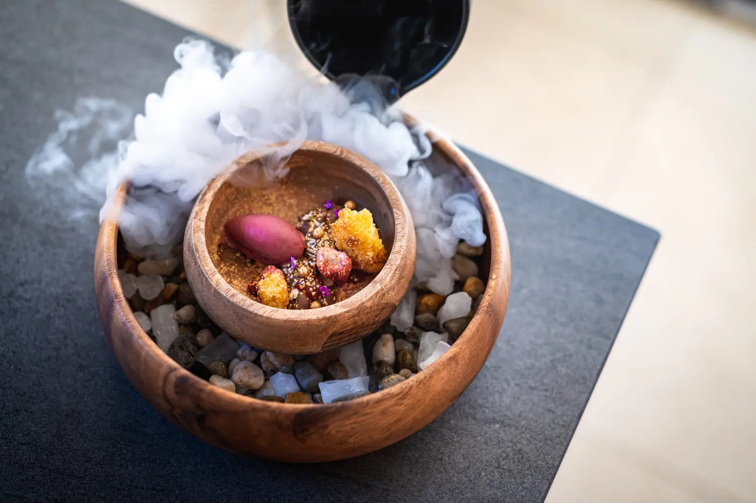 Dessert served in a wooden bowl under dry-ice smoke