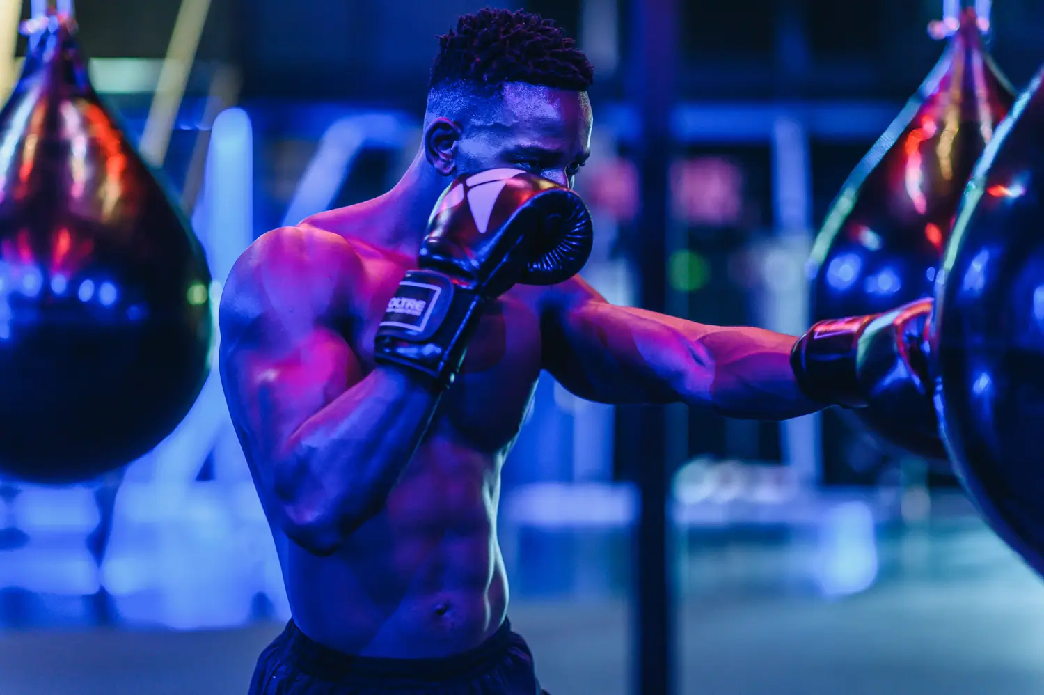 Boxer mid-punch against neon bag lighting