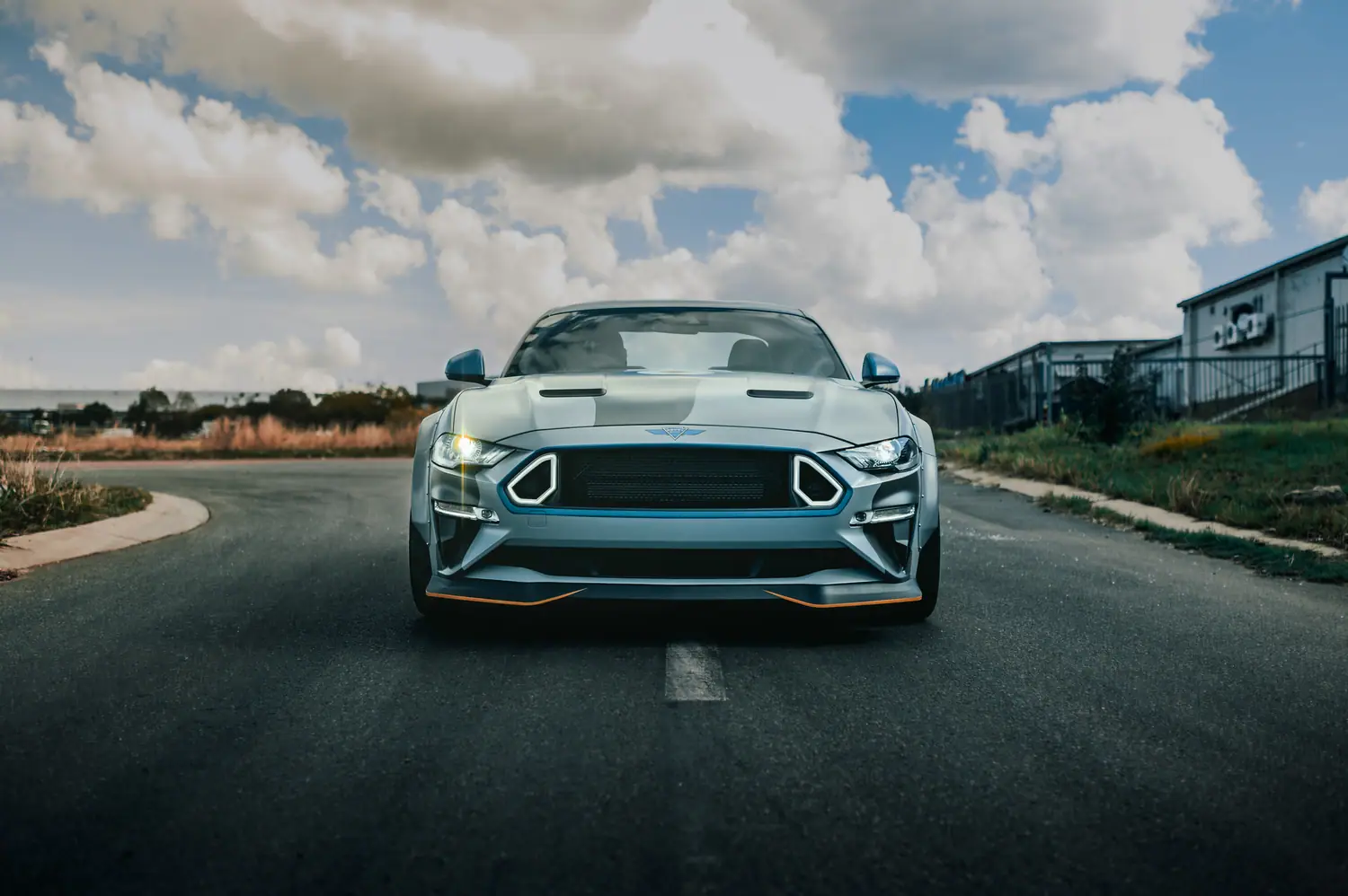 Aston Martin head-on under a wide cloud sky