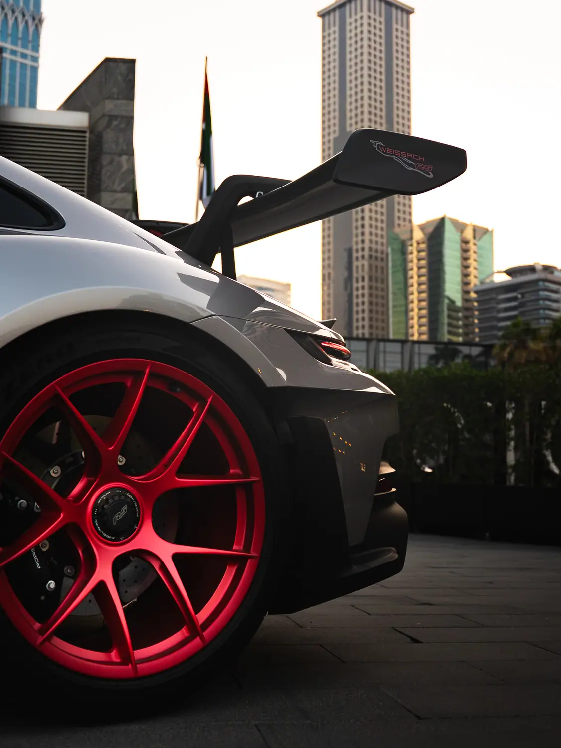Close detail of a Porsche GT3 RS rear wing and red centre-lock wheel
