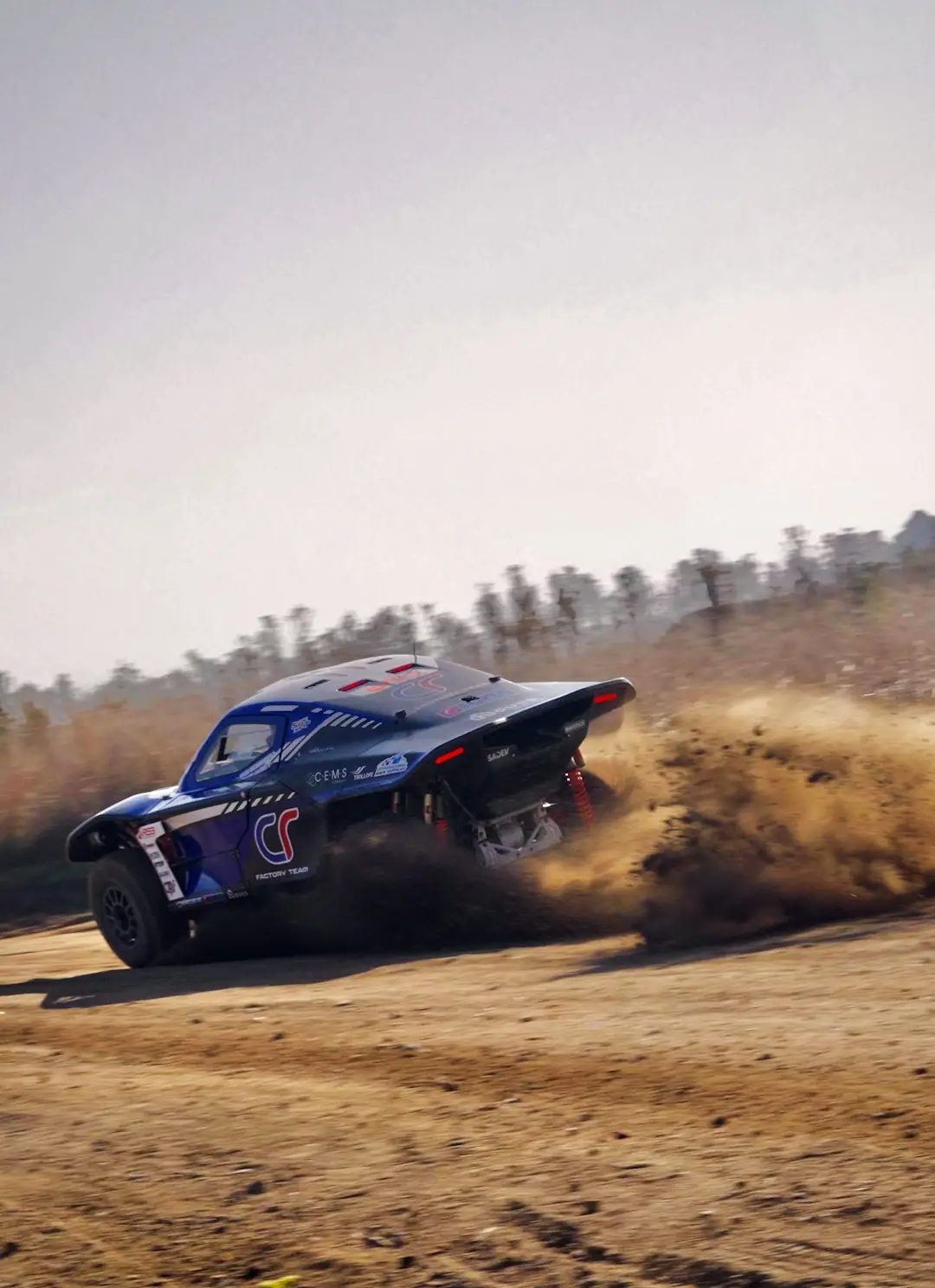 Rally car sliding through dust on a gravel stage