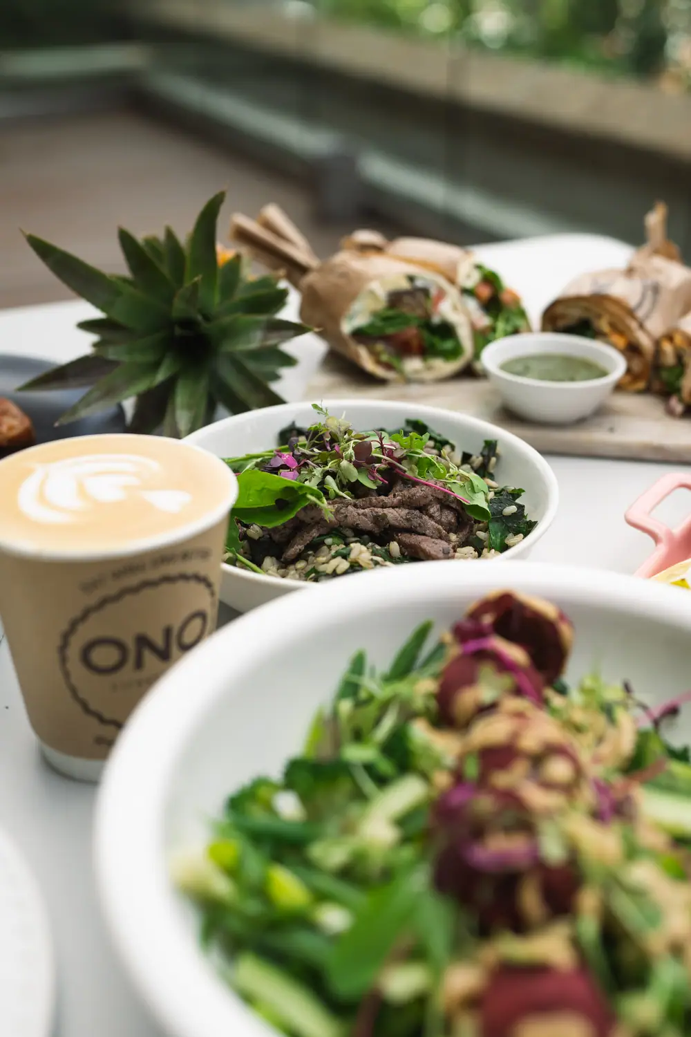 ONO branded coffee cup beside a salad bowl